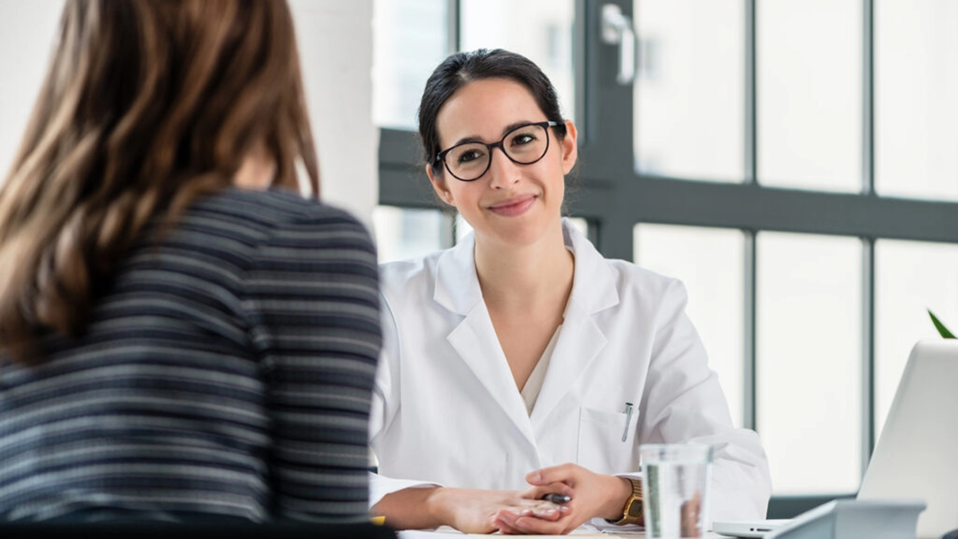 Femme médecin souriant à sa patiente lors d'une consultation médicale